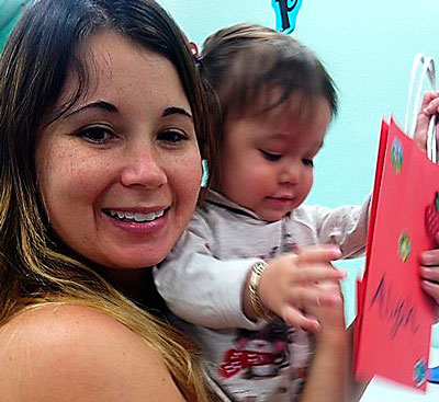A mother and her child holding up a tactile book she made at Make it Take it